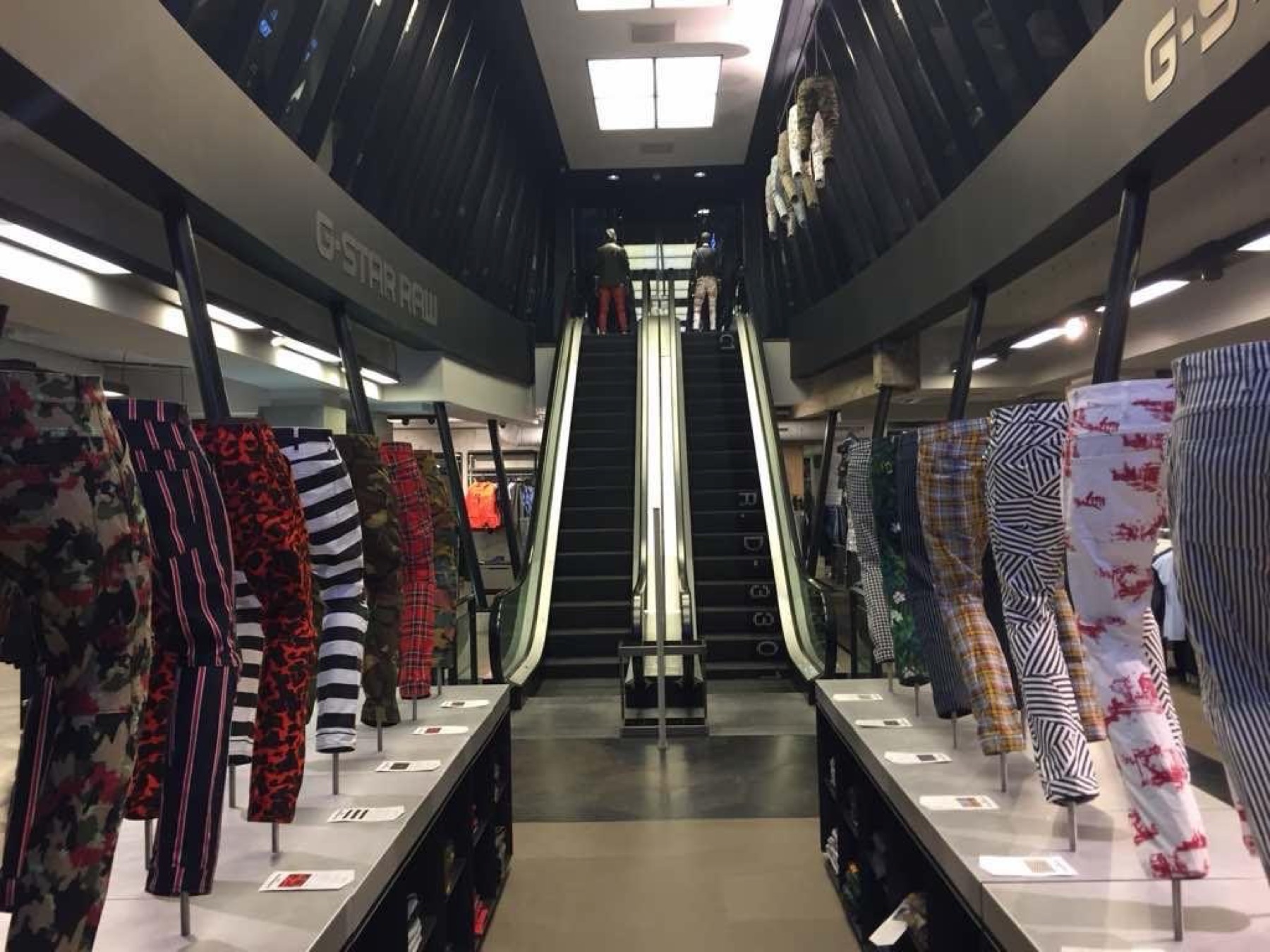Rows of printed G-Star trousers on display leading to the escalators